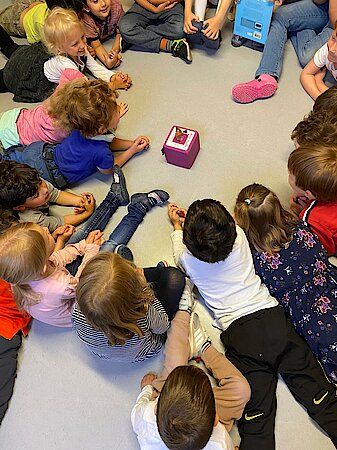 Die Kinder liegen im Kreis um die Tonie-Box und hören eine Geschichte