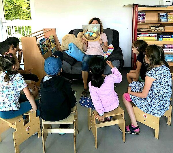 Eine Erzieherin liest einigen Vorschulkindern vor.