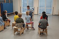 Eine Vorlesepatin liest einer kleinen Gruppe Vorschulkindern vor.