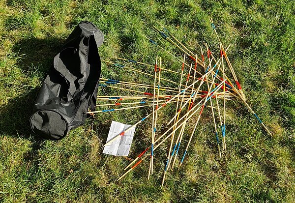 Im Gras liegendes großes Holz-Mikado-Spiel mit Tasche und Spielanleitung