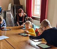 Kinder setzen mit iPads eine vorgelesene Geschichte in Szene