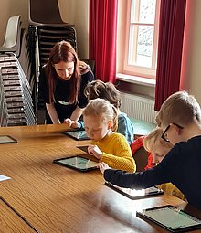 Kinder setzen mit iPads eine vorgelesene Geschichte in Szene