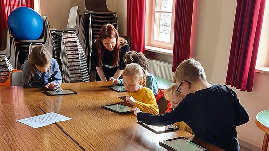 Kinder setzen mit iPads eine vorgelesene Geschichte in Szene